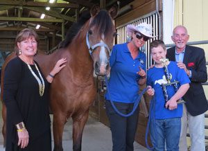 A group of people standing around a horse.