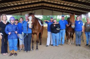 A group of people standing around two horses.