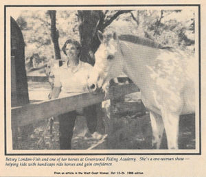 A woman standing next to a horse in the woods.