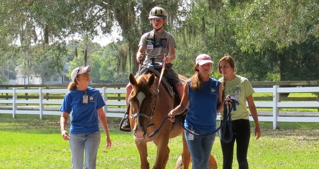 A group of people walking and riding horses.