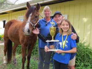 A family posing with their horse and trophy.