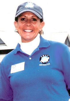 A woman in blue shirt and hat smiling for the camera.