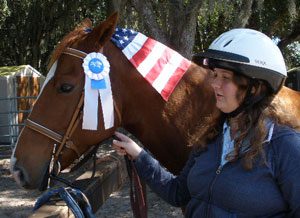 A woman is standing next to her horse.