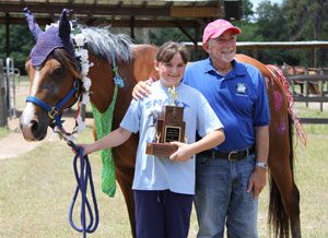 A girl holding her trophy standing next to an older man.