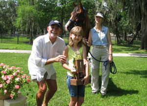 A group of people standing around with a horse.