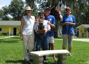 A group of people standing around a horse.