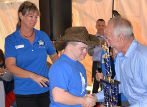 A man in blue shirt shaking hands with another person.